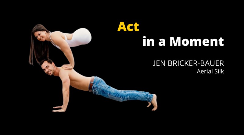 A female acrobat with no legs in a white leotard does a handstand arm press on top of another acrobat's back. He is shirtless and doing a plank