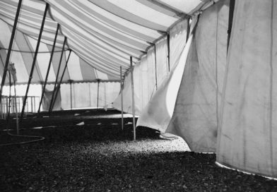 A black and white image of tent flaps held up my ratchet straps