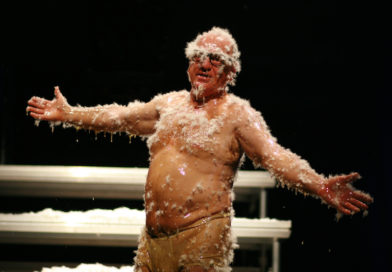 Professional clown Leo Bassi spreads his arms open while covered in honey and feathers