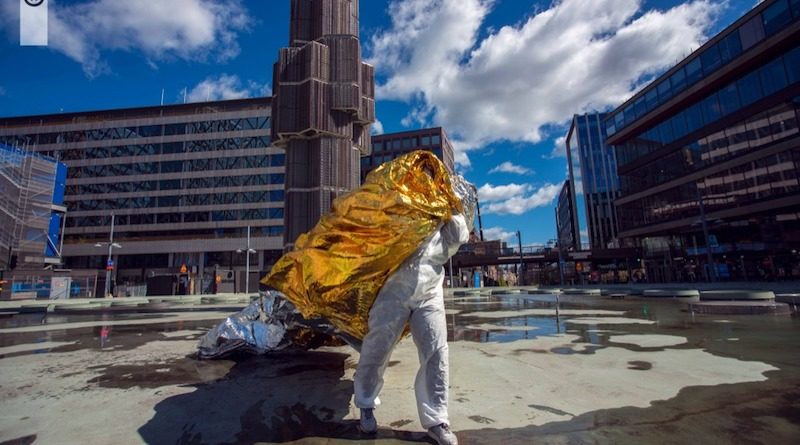 An artist stands covered in yellow