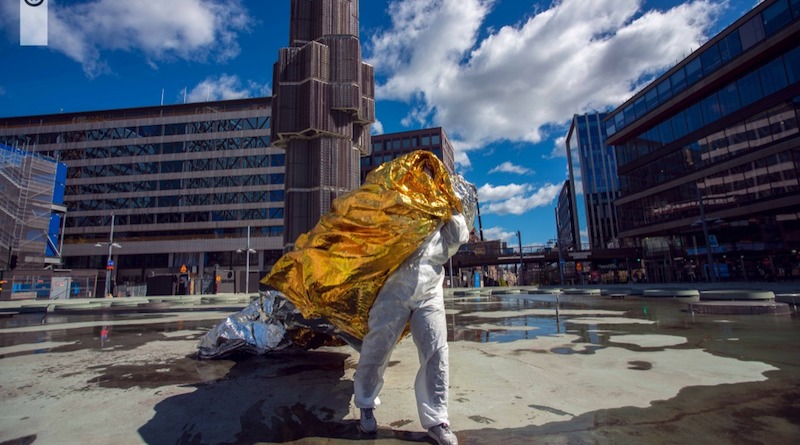 An artist stands covered in yellow