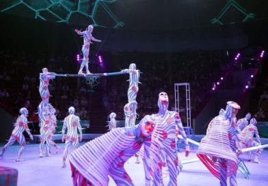 A group of performers stand on stage, with a Russian bar team taking center focus