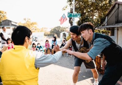 Four men stand in a group reaching out a hand to each other