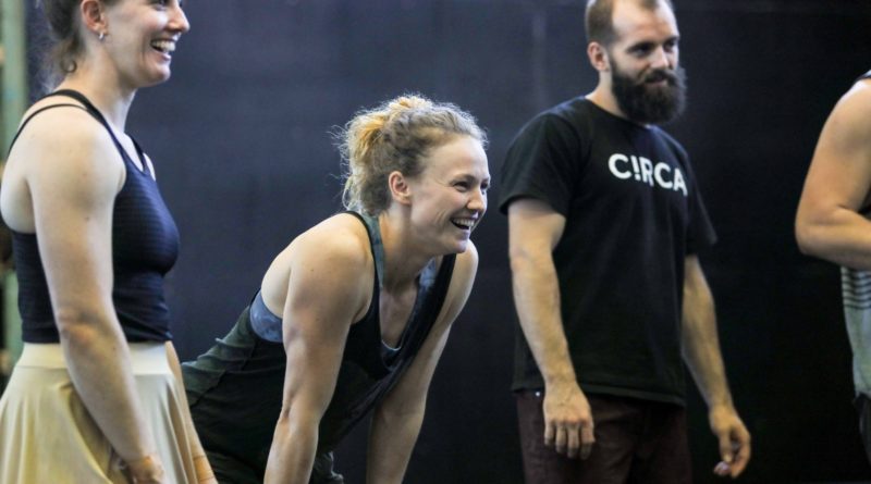 Rowan Hayden-White, profile, leans her hands on her knees and smiles. Next to her is a person with a beard wearing a black Circa tshirt.