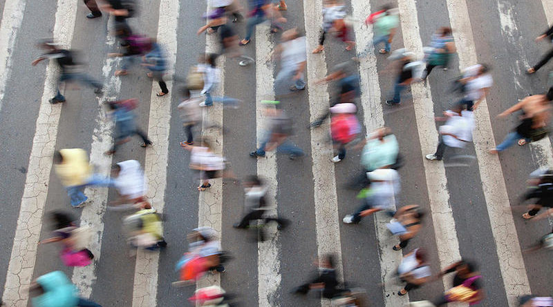 An aerial shot of a crowd of people walking through a street