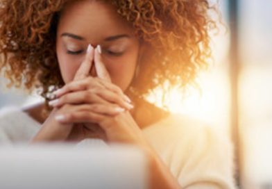 A woman holds her hands in front of her face with a headache