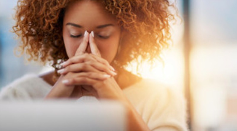 A woman holds her hands in front of her face with a headache