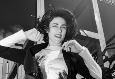 A black and white photo of a stylish young woman smiling into the camera