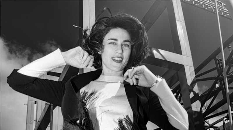 A black and white photo of a stylish young woman smiling into the camera