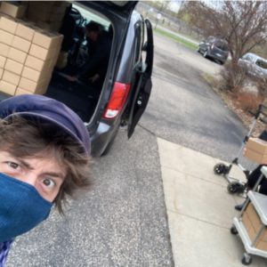 Benjamin Domask-Ruh raises an eyebrow at the open trunk of a black SUV, packed with cardboard boxes