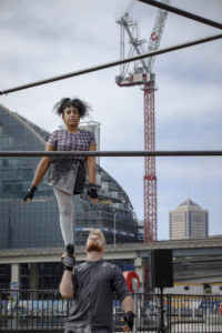 Roya the Destroya balances one-legged on Will Meager's hand at Sydney Festival