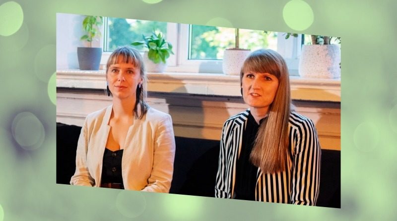 Liene Perkone and Mara Pavula sit side-by-side in front of a window