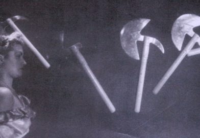 Historical circus photograph, black-and-white: a female circus performer stands against a target while axes are thrown at her