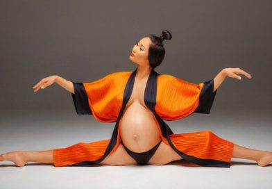 Ulzii Mergen Kee, Mongolian acrobat and circus performer, during pregnancy. She does splits in an open orange robe.