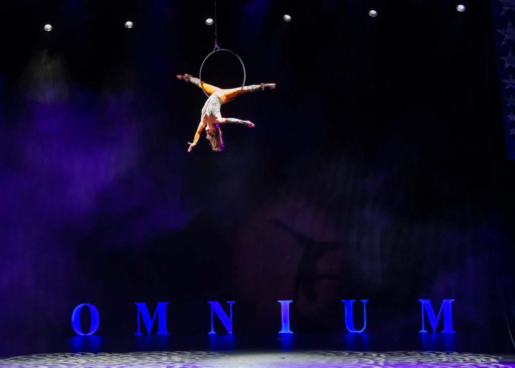 Omnium Circus performance. Vivien Espana hangs upside down from an aerial hoop suspended over the stage