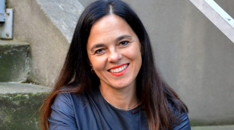 Juliana Neves, Portuguese-born circus performer and educator, sits on concrete stairs and smiles at the camera