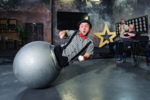 His legs inside of a moving ball apparatus, a circus performer demonstrates new theatre technology at Show Your Show 2017 event