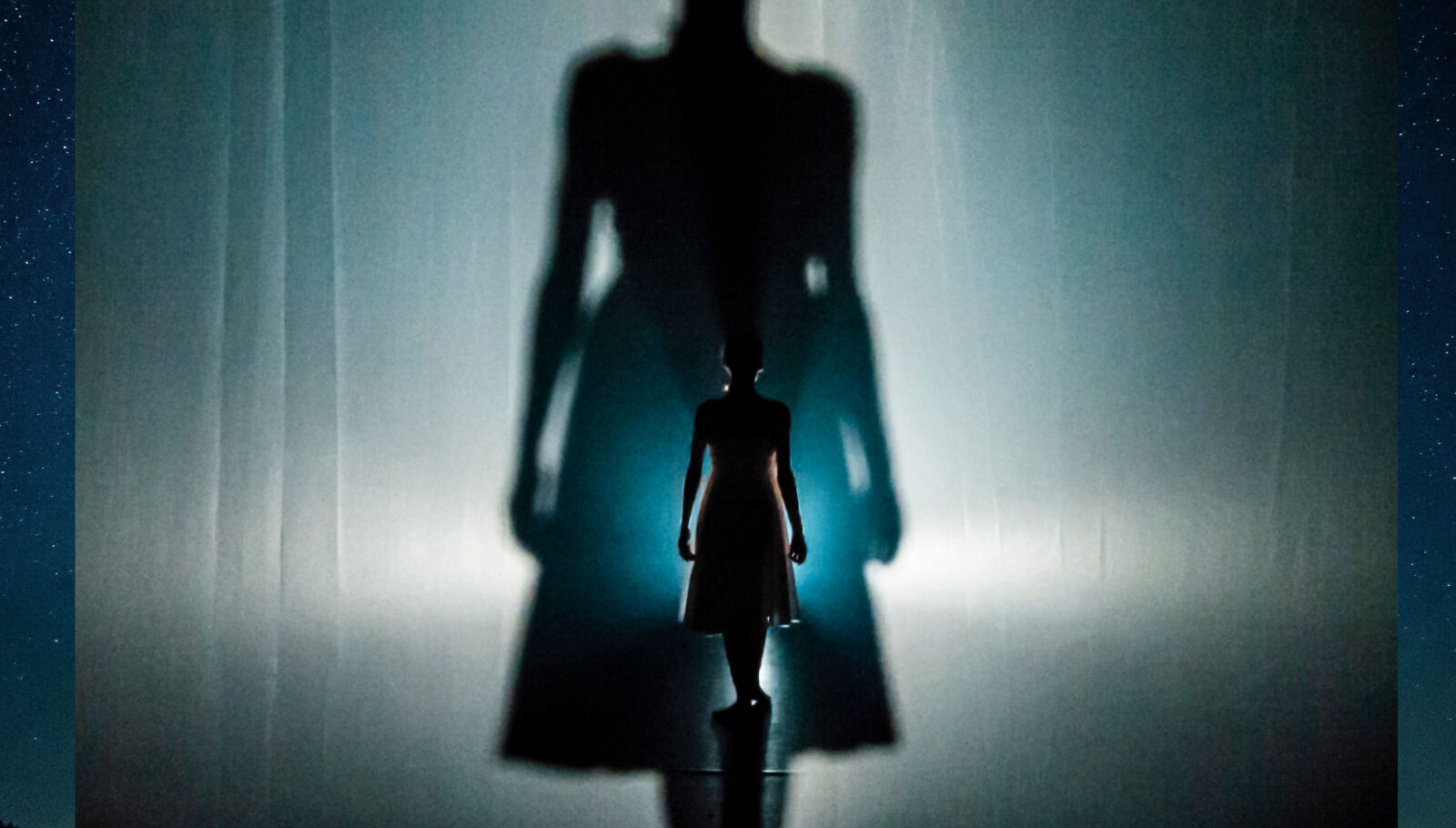 Dancer and performer Erin O'Toole onstage in "Insomniac's Fable" by Agit-Cirk. The backlit Erin is seen from behind.